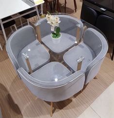 a round glass table with four chairs around it and a vase filled with flowers on top