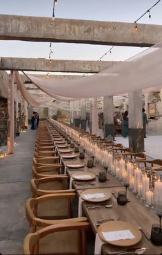 a long table with candles and plates on it is set up for an outdoor event