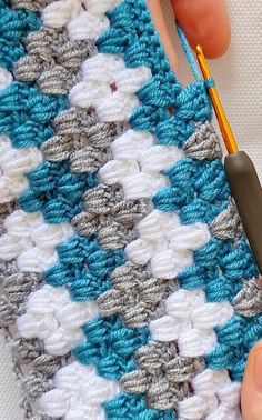 someone is crocheting the edges of a granny's afghan with a pair of scissors