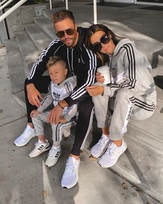 a man, woman and child are sitting on the steps with their arms around each other