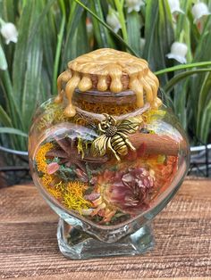 a glass jar filled with lots of different types of flowers and plants on top of a wooden table