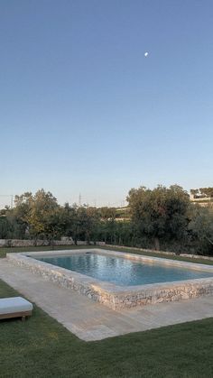 an empty swimming pool surrounded by grass and trees