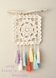 a crocheted wall hanging with tassels on it