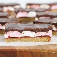 several pieces of cake sitting on top of a wooden cutting board with chocolate and marshmallows