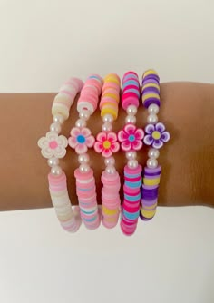 a woman's arm with several bracelets and flowers on it, all in different colors