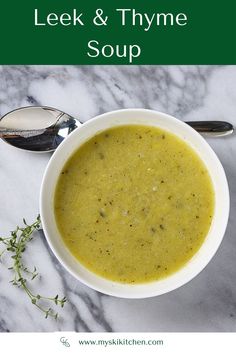 a white bowl filled with soup on top of a marble counter next to spoons