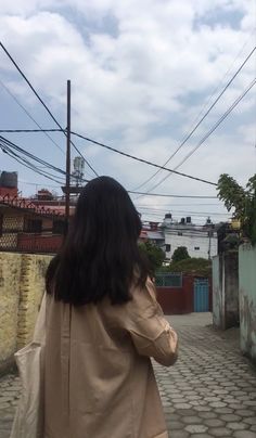 a woman walking down a cobblestone street with her back to the camera,