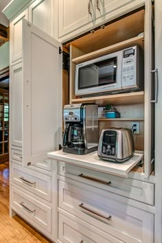 a kitchen with white cabinets and stainless steel appliances on the counter top in front of an open door