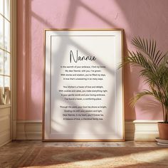 a framed poem on a wall next to a potted plant and window with pink walls