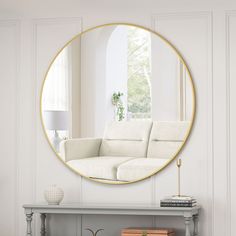 a living room with a white couch and a round mirror