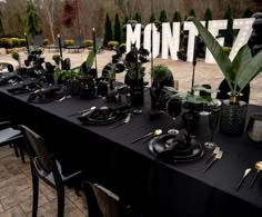 a table set up with black plates and place settings for an elegant dinner party in front of the word monte7