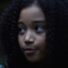 a close up of a person with curly hair looking down at her cell phone screen