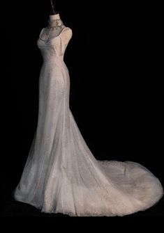 a white wedding dress on display in front of a black background with the back of it's neckline