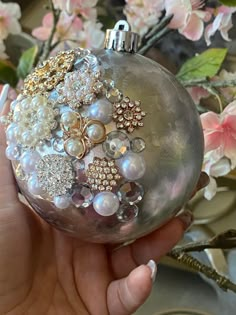 a hand holding a glass ornament with pearls