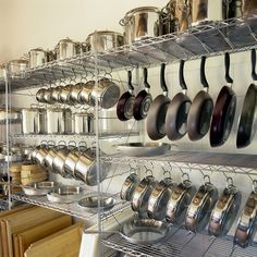 an assortment of pots and pans hanging on a rack in a kitchen with wooden cutting boards