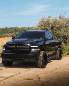 a black truck parked on the side of a dirt road