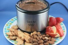 a crock pot with nuts, apples and other food on a plate next to it