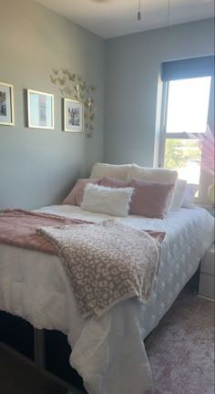 a bedroom with a bed, window and pictures on the wall above it's headboard