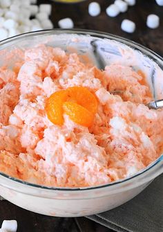 a bowl filled with food next to marshmallows and an orange on top