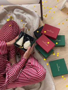 a woman in red and white pajamas sitting on the floor next to some green boxes