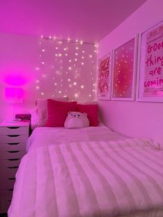 a bedroom with pink lights and pictures on the wall above the bed, along with a teddy bear