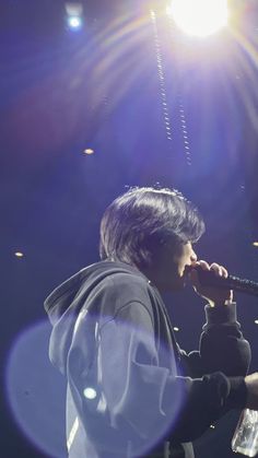 a man holding a microphone up to his mouth while standing in front of a stage