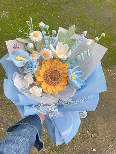 a person holding a bouquet of flowers in their hand on top of a field with grass