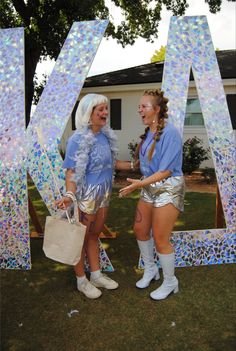 two women standing next to each other in front of letters