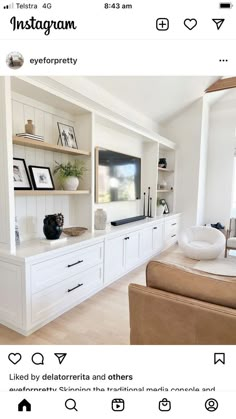 an image of a living room with white furniture and shelves on the wall, including a flat screen tv