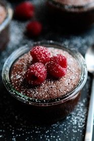 chocolate pudding with raspberries and powdered sugar in a glass bowl on a table