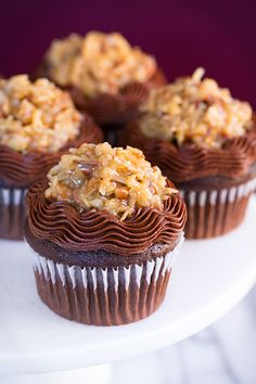 several chocolate cupcakes on a white cake plate