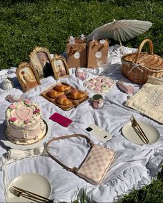 a picnic table is set up on the grass with food and drinks, including cakes