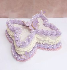 two purple and white butterfly shaped cookies sitting on top of a table