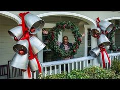 three bells with red bows on them are hanging from the side of a house in front of christmas wreaths