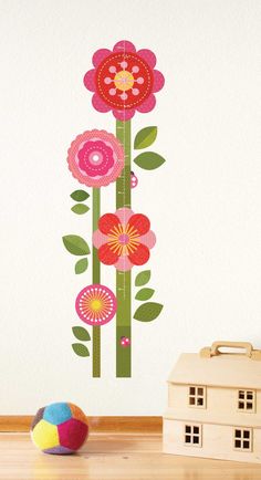 a wall sticker with flowers on it next to a toy house and a ball