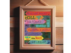 a wooden frame hanging on the wall with some colorful signs in front of it that say,