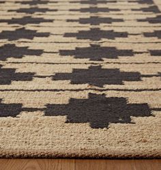 an area rug with black and white designs on it, sitting on a wooden floor