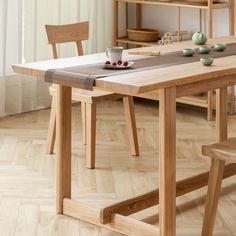 a wooden table with two chairs and a bowl of cherries on the table next to it