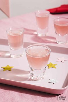 three glasses filled with pink liquid sitting on top of a tray