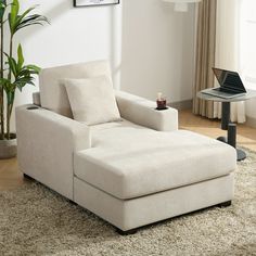 a white couch sitting on top of a rug in a living room next to a laptop computer