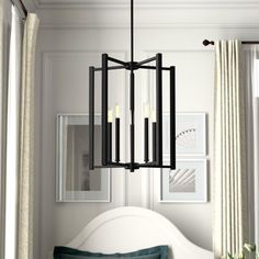 a chandelier hanging over a bed in a room with white walls and curtains