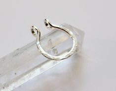 a silver ring sitting on top of a clear piece of glass with a white background