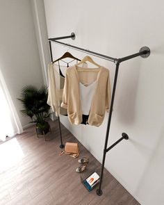 clothes are hanging on a rail in the corner of a room next to a window