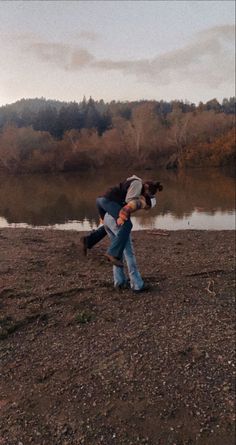 two people are playing with a frisbee by the water