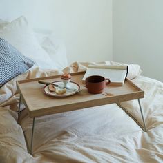 a tray with food on it sitting on top of a bed next to a pillow