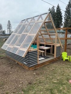 a small house with a roof made out of corrugated sheets and a greenhouse attached to it