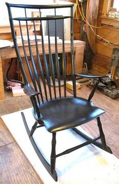 a black rocking chair sitting on top of a wooden floor