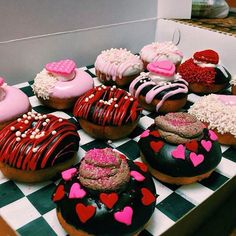 a box filled with lots of different flavored donuts on top of a checkered table