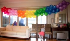 a woman and child are standing in the living room with balloons on the wall above them