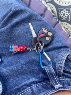 a car keychain attached to a pair of blue jean shorts with red and white keys